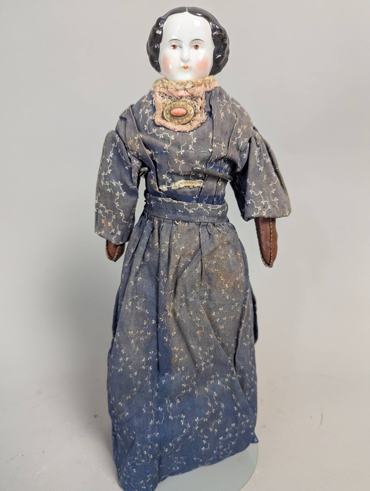 Antique Porcelain Doll with Black Hair and Aged Fabric Clothing